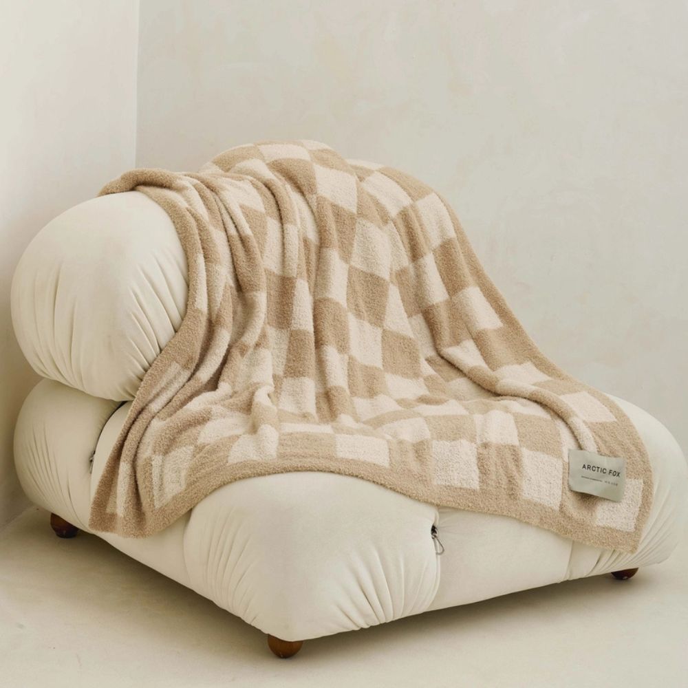 super soft teddy fleece throw with chequerboard pattern shown draped over a while sofa