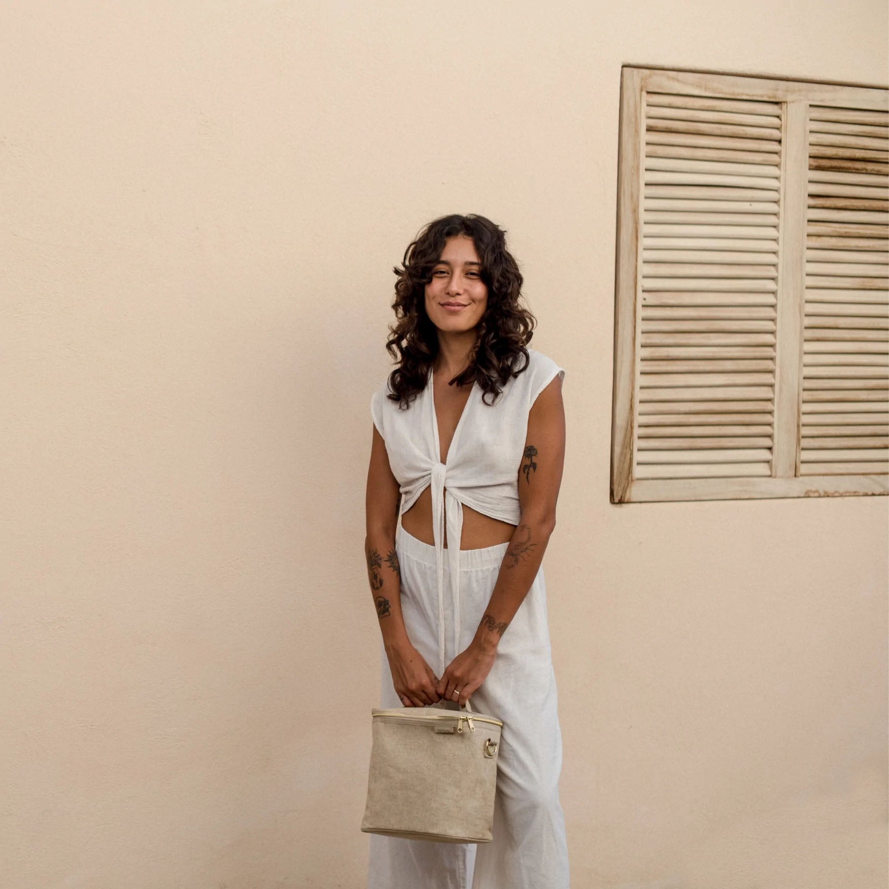 woman holding the linen lunch bag with a neutral wall in the background
