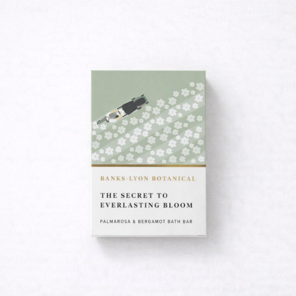 A boxed bath bar product standing upright on a light neutral background. The package is white and pale sage green with white floral graphics and gold text reading 'BANKS-LYON BOTANICAL' and 'THE SECRET TO EVERLASTING BLOOM'.