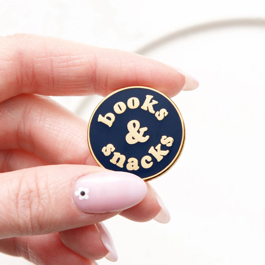 Holding the books and snacks badge between two fingers