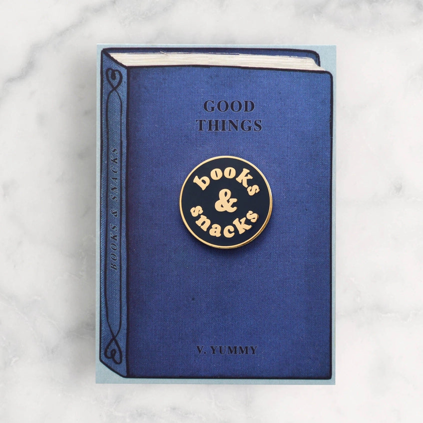 The books and snacks badge on its backing card that's designed to look like a blue hardback book with the title 'good things' by v.yummy