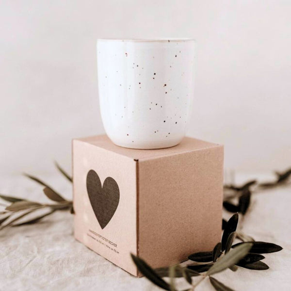 White speckled handleless mug on top of brown gift box