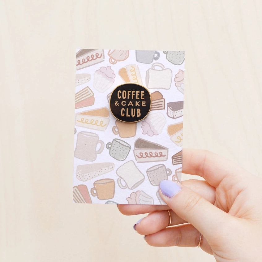 Holding the coffee & cake club badge on its backing card.