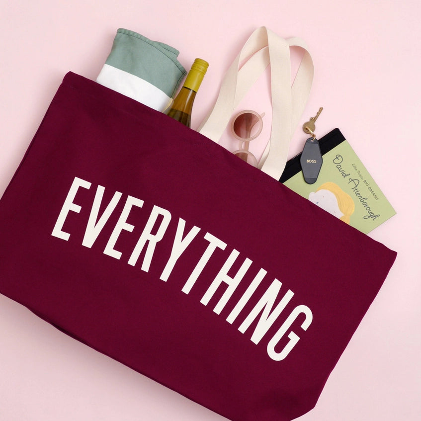 Flat lay of the extra large tote bag, showing a bottle, sunglasses, car keys, book and towel poking out.