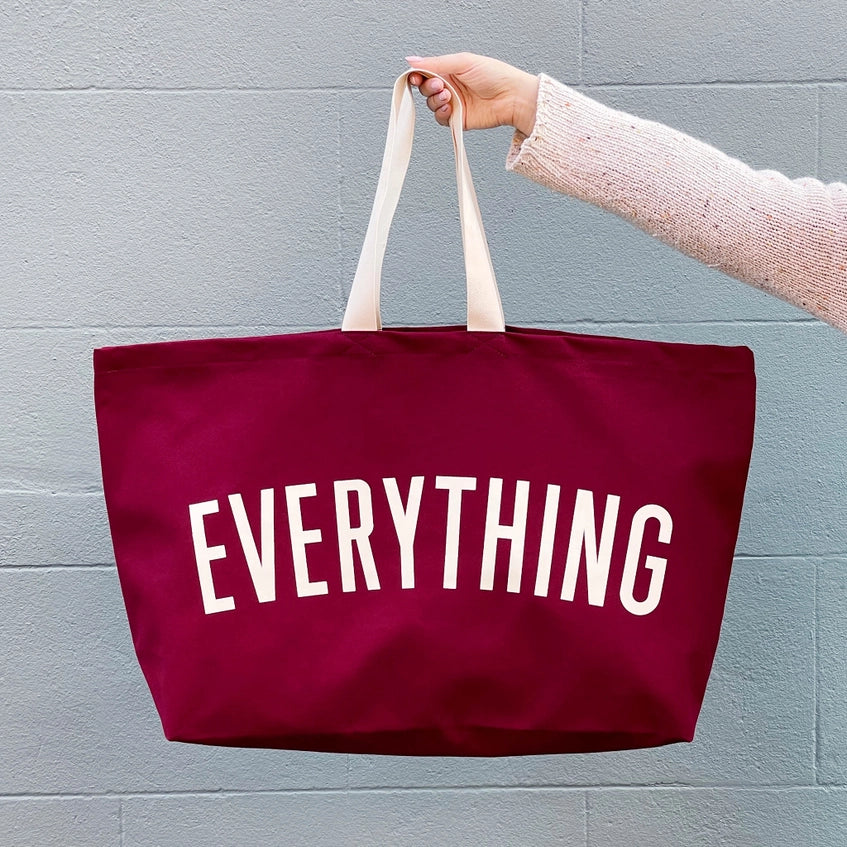 Holding the red oversized tote bag up against a blue wall