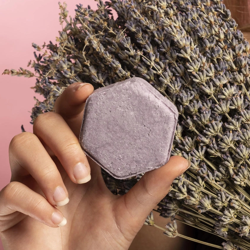 Woman holding the purple shower bar in her hand with lavender in the background