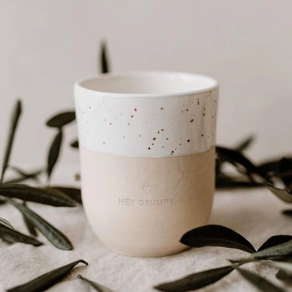 White speckled handleless mug with the words 'hey grumpy' stamped on the front