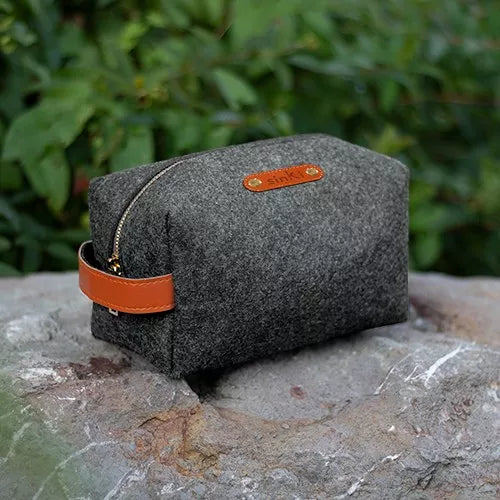 Antracite grey mens wash bag in eco felt placed on a boulder