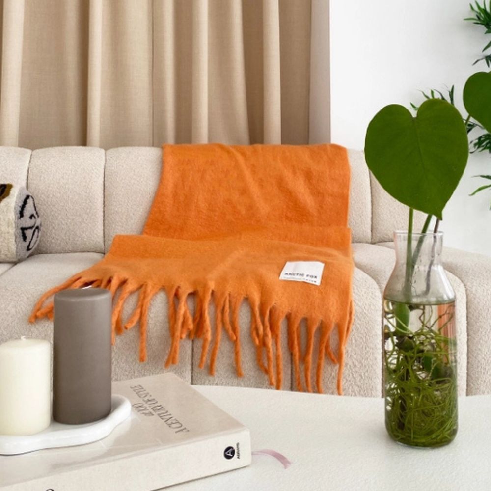 The orange throw draped over a cream sofa