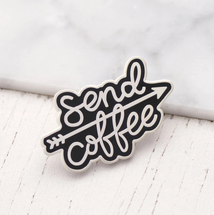 Black and silver coloured pin badge, with an arrow running between the words Send and Coffee. Both words are in a hand-written font.