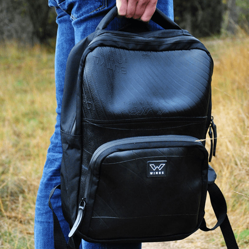 Man holding the upcycled backpack by the top carry handle